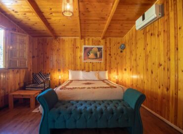 Bungalow Double bedroom with wood-paneled walls and teal tufted bench at Dar l'Eau Vive guest house